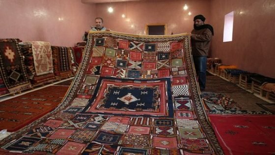 تتحرك أناملها بخفة بين خيوط الصوف الملونة، تردد بلحن هامس أغنية أمازيغية قديمة، برودة الطقس ونسمات البرد التي تلفح يديها لا تحد من حماسها وهي ترسم بأناة "إكلان" قبيلتها (رموز القبيلة بالأمازيغية) بخيوط الصوف الرفيعة، التي قضت في صباغتها أياما وفي نسجها ساعات متواصلة، تبدأ مع تباشير الصباح ولا تنتهي إلا وقد غرقت قريتها " تازناخت" الواقعة على تخوم الصحراء في الظلام الدامس. (Jalal Morchidi - Anadolu Ajansı)